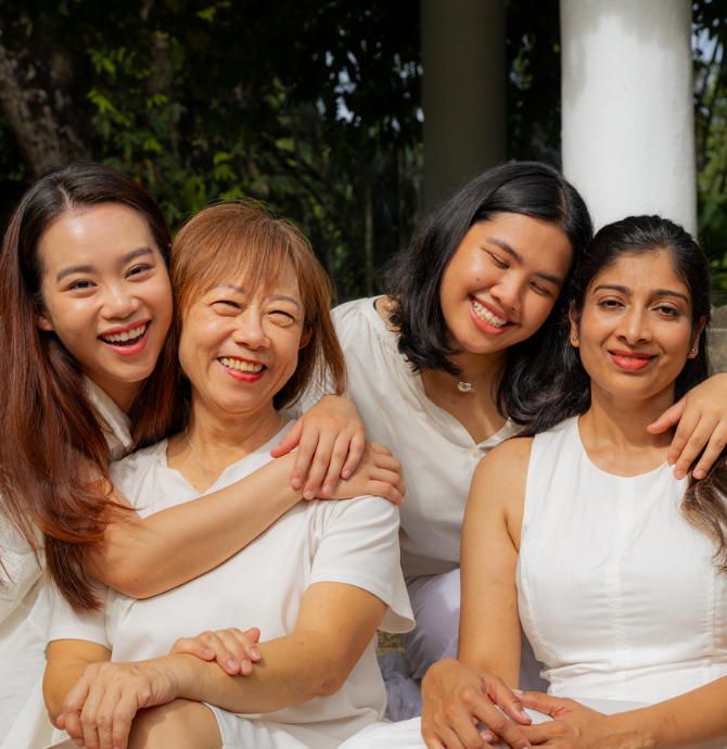 Four women posing together outdoors, smiling.